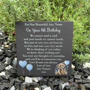 May include: A square black slate plaque featuring white printed text that reads For Our Beautiful Any Name On Your 6th Birthday, followed by a memorial poem, and ending with Any Name/s XXX. The design includes two light blue balloons and a teddy bear.
