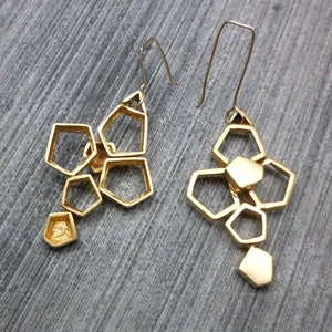 May include: A pair of gold geometric earrings with a honeycomb design. Each earring features multiple interconnected hexagonal shapes.