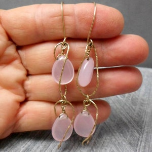 May include: A pair of dangle earrings with pink glass beads wrapped in gold wire.
