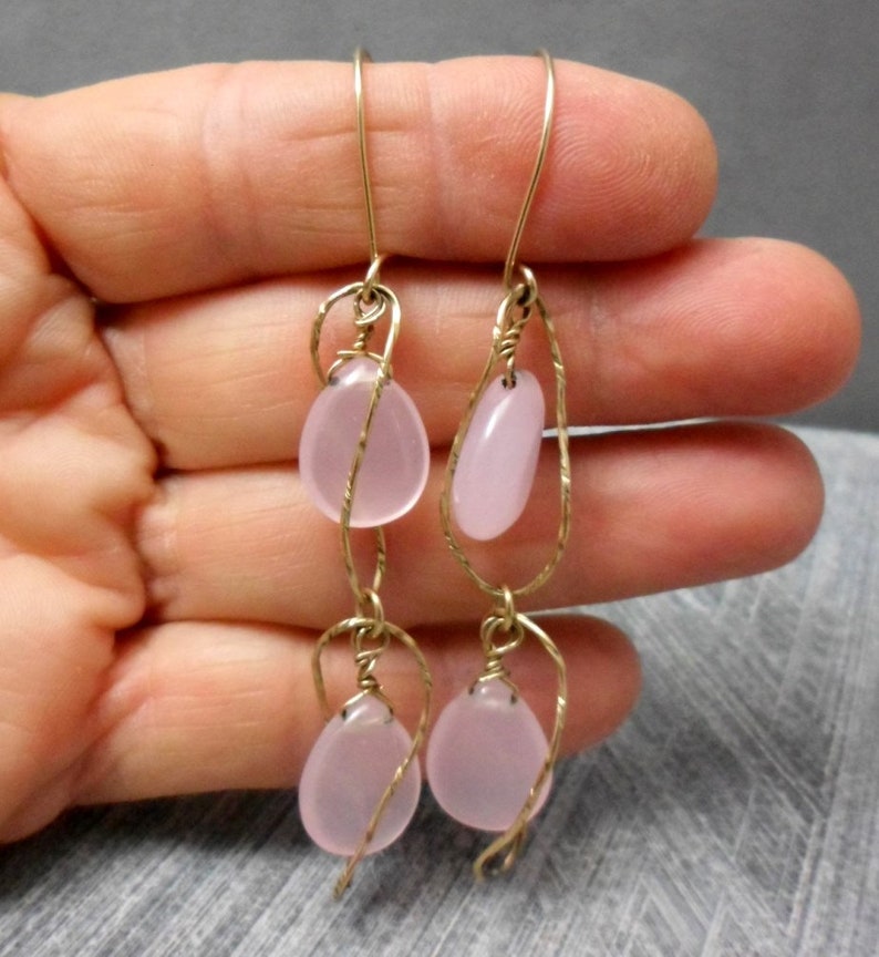 May include: A pair of dangle earrings with pink glass beads wrapped in gold wire.