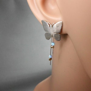 May include: Silver butterfly earrings with a dangling chain of opal and gold beads.