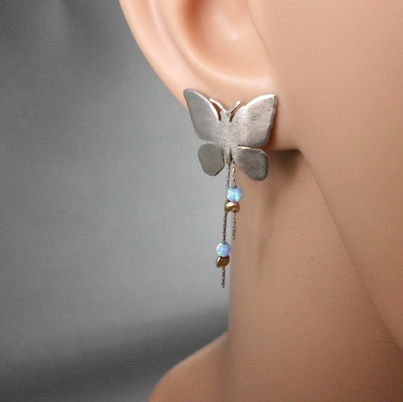 May include: Silver butterfly earrings with a dangling chain of opal and gold beads.