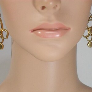 May include: Gold geometric dangle earrings with a honeycomb design.