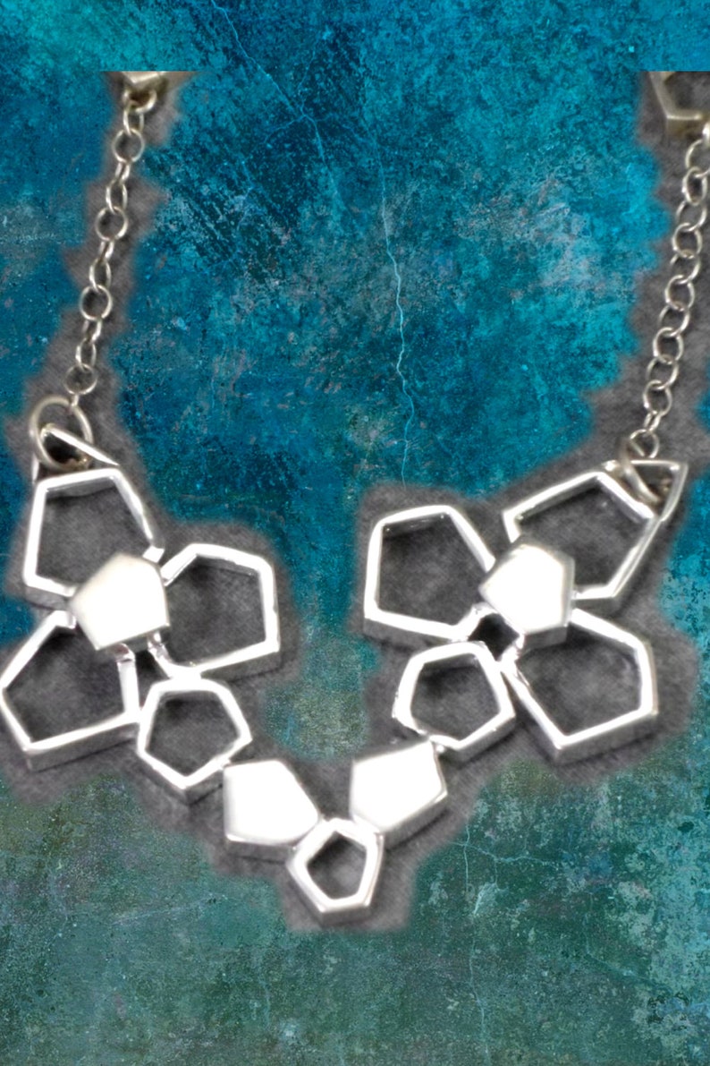 May include: A silver necklace with a geometric design. The necklace is made up of multiple interconnected hexagonal shapes.