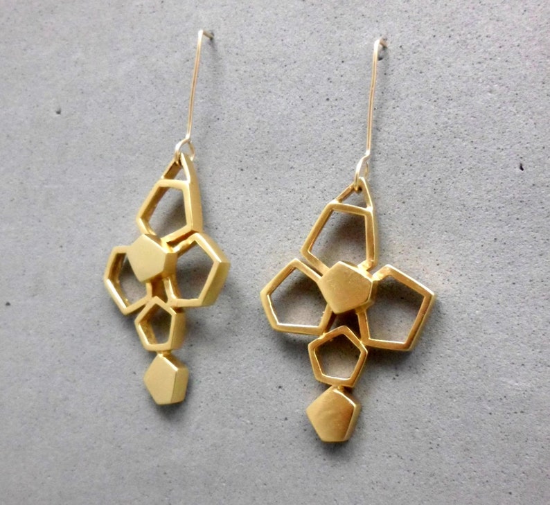 May include: A pair of gold geometric earrings with a cluster of hexagonal shapes hanging from a thin wire.