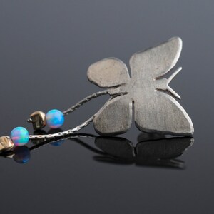 May include: A silver butterfly pendant with a chain and three iridescent blue opal beads.