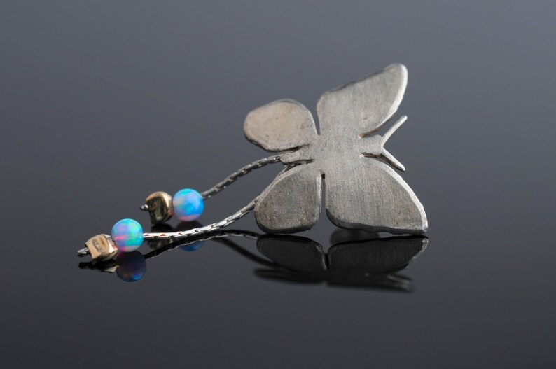 May include: A silver butterfly pendant with a chain and three iridescent blue opal beads.