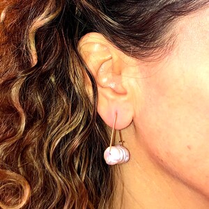 May include: A pair of earrings with a single, large, iridescent pearl-like drop on each earring. The earrings are made of gold-toned metal and have a simple, minimalist design.