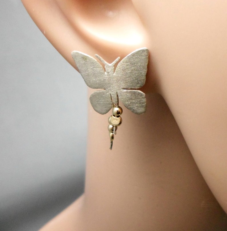 May include: Silver butterfly earrings with a dangling chain of gold beads.