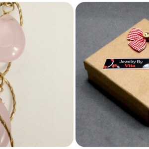 May include: A pink rose quartz necklace with gold wire wrapping. The necklace is packaged in a brown box with a red and white gingham bow and a label that reads "Jewelry By Vita".
