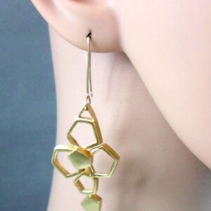 May include: Gold geometric dangle earrings with a cluster of interconnected hexagonal shapes.