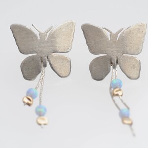 May include: Silver butterfly earrings with dangling chains and opal beads.