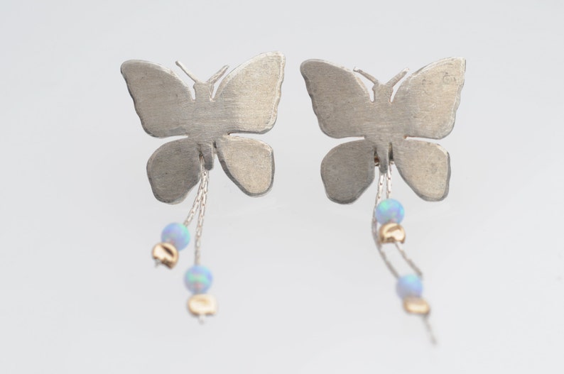 May include: Silver butterfly earrings with dangling chains and opal beads.