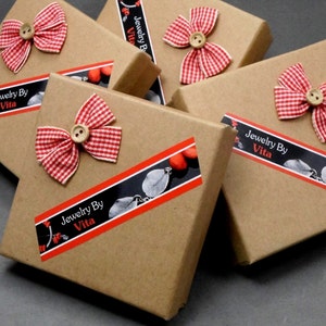 May include: Multiple brown cardboard boxes with red and white gingham bows and a black and white label that reads "Jewelry By Vita".