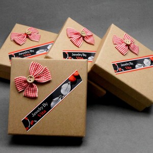 May include: Four small brown cardboard boxes with red and white gingham bows and a label that reads "Jewelry By Vita".