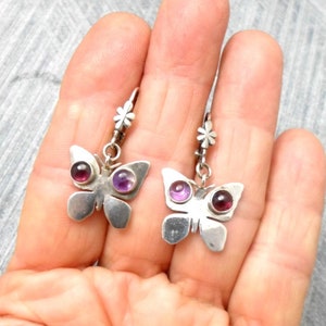 May include: A pair of silver butterfly earrings with purple gemstone accents.