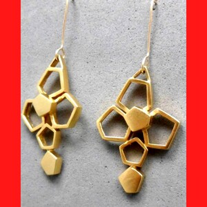 May include: A pair of gold geometric earrings with a dangling design. Each earring features a cluster of interconnected hexagonal shapes.