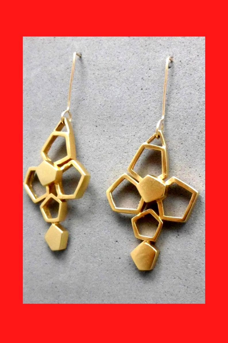 May include: A pair of gold geometric earrings with a dangling design. Each earring features a cluster of interconnected hexagonal shapes.