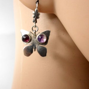 May include: Silver butterfly earrings with purple and red gemstone accents.