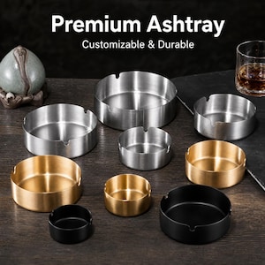 Op de afbeelding: Een collectie ronde asbakken in verschillende maten en afwerkingen, waaronder geborsteld zilver, goud en matzwart metaal. De tekst "Premium Ashtray" en "Customizable & Durable" is zichtbaar bovenaan de afbeelding boven de metalen houders.