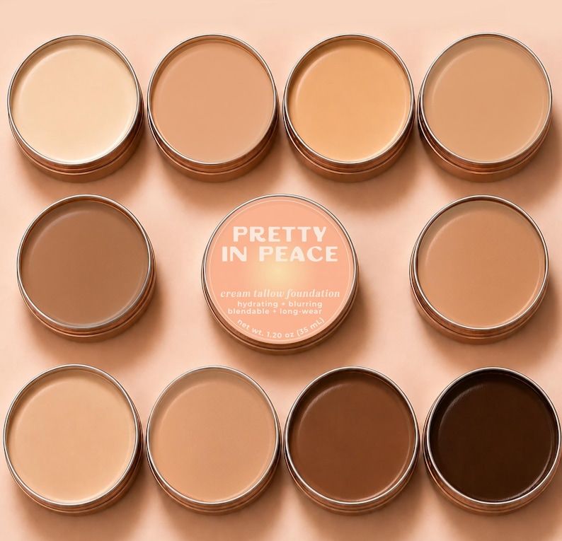 May include: Nine round metal tins containing cream tallow foundation in various skin tones. The center tin features a peach label with the text PRETTY IN PEACE, cream tallow foundation, hydrating + blurring, blendable + long-wear, net wt. 1.20 oz.