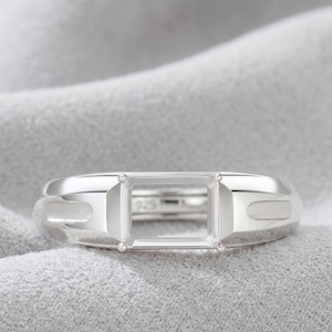 May include: A silver ring setting featuring a rectangular prong mount for a gemstone. The band has a polished finish with recessed side details and is stamped with 925 on the inner surface, indicating sterling silver construction for jewelry.
