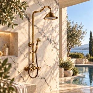 May include: A wall-mounted shower system in a brushed brass finish featuring a large overhead rainfall showerhead, a handheld shower wand with a flexible hose, and two cross-handle valves for water control, all mounted on a marble-tiled wall.