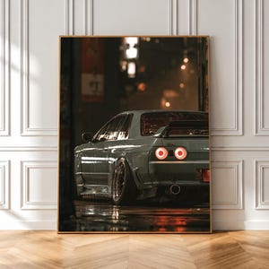 May include: A rectangular wall art print featuring a rear view of a light grey sports car parked on a wet city street at night. The vehicle displays glowing circular red taillights, a rear spoiler, and wide wheels, set against a dark urban background.