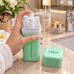 May include: A mint green travel kit container with four white pump dispensers inside. The container features a vertical cutout to view contents and a matching mint green lid with the name Chloe printed in black on the top surface of the lid.