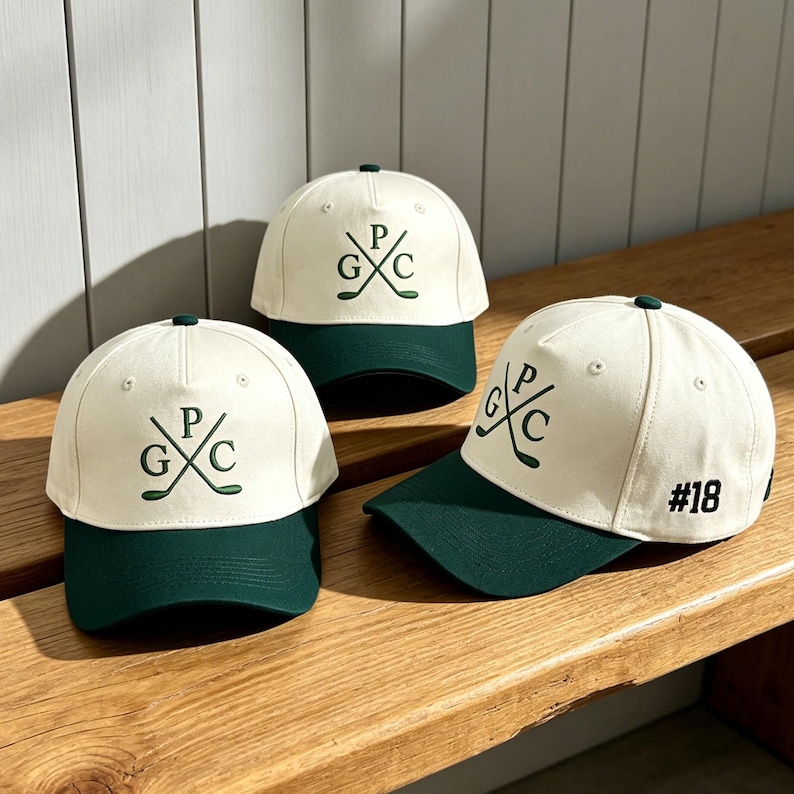 May include: Three baseball caps with off-white crowns and dark green brims. Each cap features a dark green embroidered logo of two crossed golf clubs with the letters G, P, and C. One cap displays the number #18 in black on the side panel.