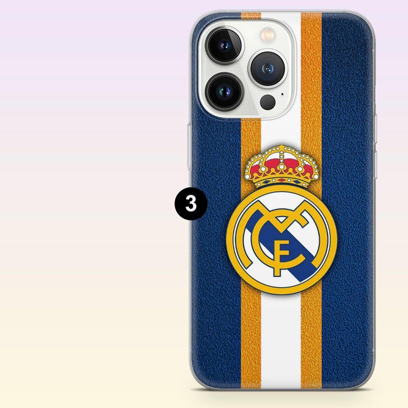 May include: A smartphone case featuring a textured dark blue background with vertical white and gold stripes. Centered on the case is the Real Madrid football club logo, which includes a gold crown above a circular emblem with the letters MCF.