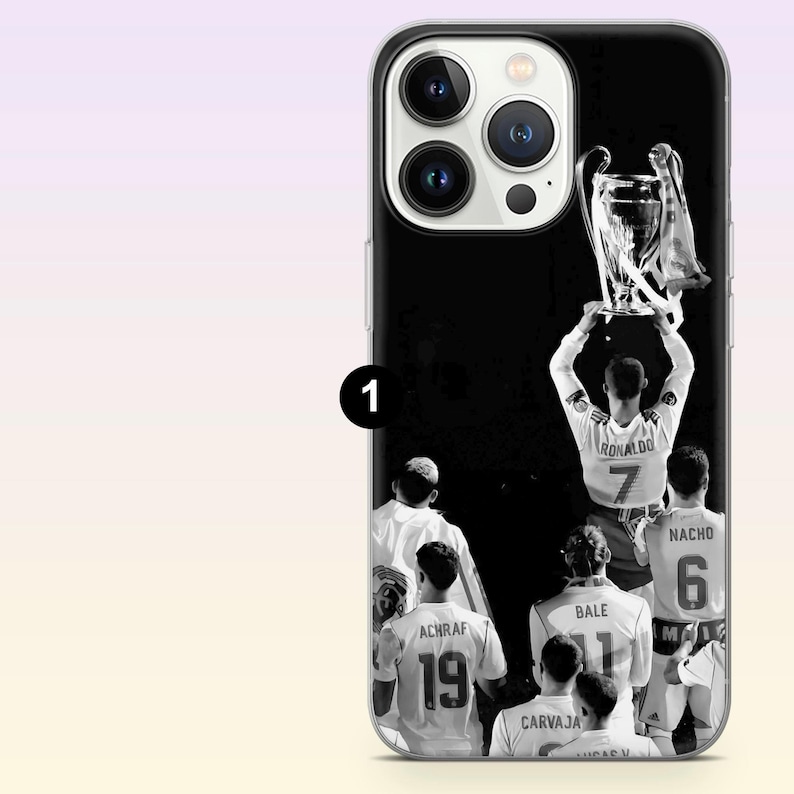 May include: A black and white phone case featuring a group of soccer players in jerseys with names and numbers including Ronaldo 7, Bale 11, Nacho 6, Achraf 19, and Carvajal. The players are shown from behind, with one player lifting a large trophy.