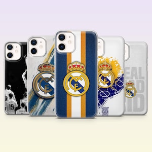 May include: Five smartphone cases featuring Real Madrid branding. Designs include a black and white player photo, a blue and gold striped pattern, a yellow and blue graphic, and a white case with the text REAL MADRID, all displaying the club crest.