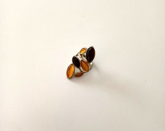 May include: A silver ring with multiple oval-shaped stones. The stones are a mix of amber and black.