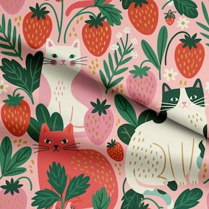 May include: A fabric pattern featuring a repeating design of white and red cats interspersed with red strawberries, green leaves, and small white flowers on a light pink background. The cats have detailed whiskers and simple facial features.
