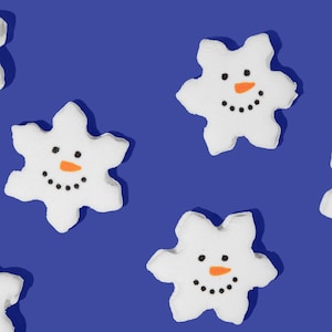May include: Five white snowflake-shaped marshmallows with orange noses and black eyes and mouths on a blue background.