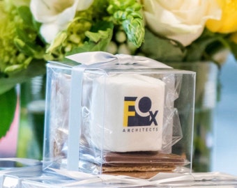 May include: Three clear plastic boxes with white marshmallows inside. Each marshmallow has a blue and yellow logo that says "Fox Architects". The boxes are stacked on top of each other.