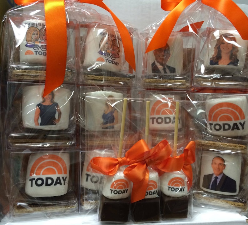 May include: Clear plastic packaging containing s'mores with marshmallows printed with the "Today" show logo and images of the show's hosts. The s'mores are tied with orange ribbons. The marshmallows sit on graham crackers and chocolate.