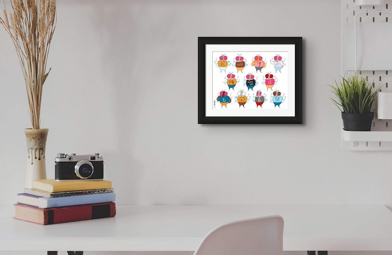 May include: A framed print featuring a colorful illustration of 12 cartoon flies wearing different outfits and numbers. The flies are all smiling and have large, round eyes.