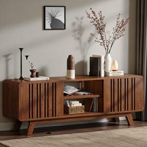 May include: A long, rectangular wooden media console featuring rounded edges, vertical slat cabinet doors, and an open center shelf. The console is supported by four angled legs and holds various decorative items, including books, a vase, and a basket.