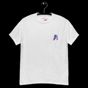 May include: A light gray heather crew neck t-shirt featuring a small embroidered graphic of the blue character Sonic the Hedgehog running on the left chest area. The inner neck label displays the text Retro Ripp in a rectangular box design.