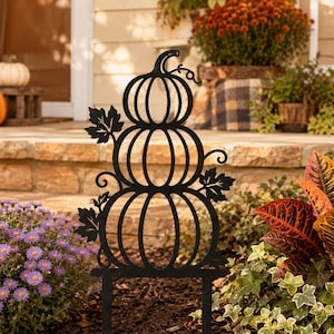 Könnte beinhalten: Ein schwarzer Gartenstecker aus Metall mit einem Motiv aus drei vertikal gestapelten Kürbissen. Die Silhouette ist mit dekorativen Blatt- und Rankenverzierungen an den Seiten versehen und hat zwei Spitzen zur Befestigung im Boden.