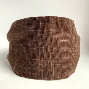 May include: A brown linen face mask. The mask is made of a soft, breathable fabric and has a simple, rectangular shape.