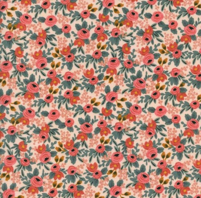 May include: A floral fabric featuring a repeating pattern of pink roses, small orange buds, and green leaves on a cream background. The design has a vintage aesthetic, suitable for quilting or crafting projects.