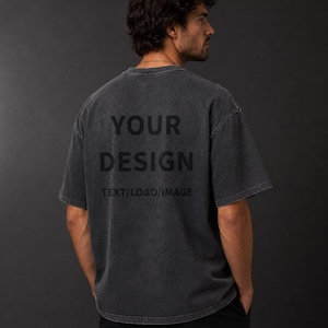 Puede incluir: Una camiseta de manga corta en color gris carbón con un acabado desgastado. La parte posterior presenta el texto negro "YOUR DESIGN" seguido de "TEXT/LOGO/IMAGE" impreso en una fuente sans-serif, centrado en la parte superior de la espalda.