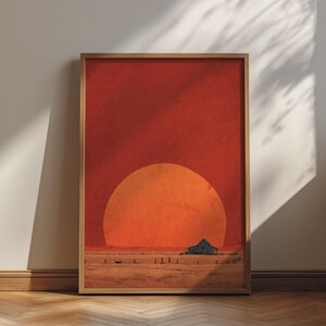 Può includere: Una stampa artistica verticale incorniciata che raffigura un vasto paesaggio piatto sotto un cielo rosso intenso con un grande sole arancione brillante che tramonta all'orizzonte. Un piccolo fienile rustico scuro si trova in un campo dorato.
