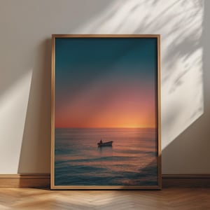 Könnte beinhalten: Ein gerahmter Kunstdruck, der ein kleines Boot zeigt, das bei Sonnenuntergang auf einem ruhigen Ozean schwimmt. Der Himmel verläuft von einem tiefen Blau oben zu einem leuchtenden Orange am Horizont, das sich auf den sanften Wellen spiegelt.