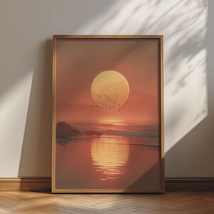 Könnte beinhalten: Ein rechteckiger gerahmter Kunstdruck, der einen Sonnenuntergang über einem ruhigen Ozean zeigt. Die Szene zeigt eine große, blassgelbe Sonne über dem Horizont, unter der ein Vogelschwarm fliegt. Das Wasser reflektiert das warme orangefarbene Licht.