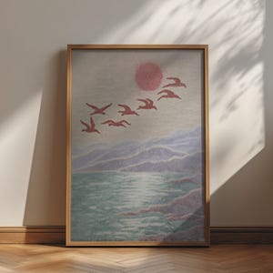 May include: A framed wall art print featuring a textured landscape scene with a large pink sun, a flock of birds flying in formation, rolling purple hills, and a light blue body of water with a reflective surface, all enclosed in a light wood frame.