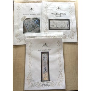 May include: Three white paper cross stitch pattern booklets from The Wishing Thorn. The top left is Mysterious M Sampler 1800s, the top right is Woodland Walk Sampler, and the bottom is Motif Sampler 1820s, each featuring a printed image of the design.